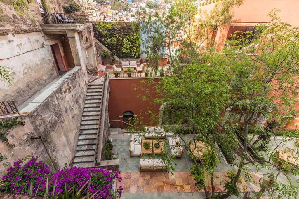 the internal patio of a luxury hotel with bugainvilleas and stairs - Where to stay in Guanajuato