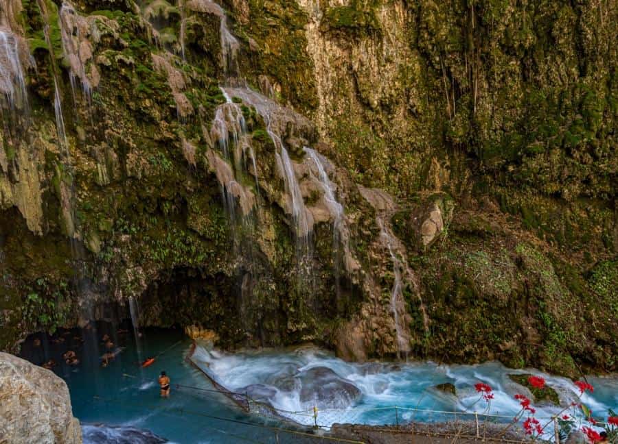waterfalls and river with people at the bottom in a cave