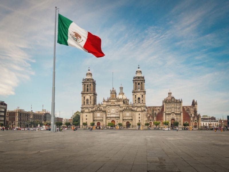 The front of the cathedral in the Zocalo Mexico with a giant Mexican flag