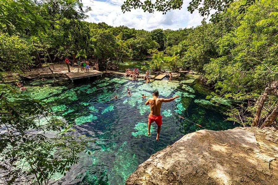 boy jumping from the trampoline to the cenote