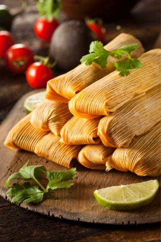 Tamales on a wooden plate.