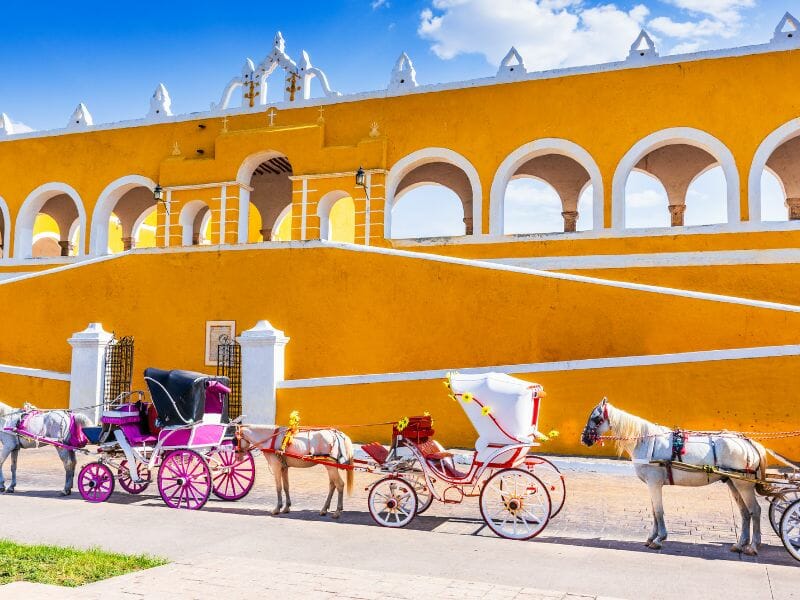 Yellow-coloured convent of Saint Padua in Izamal with horse carriages in front
