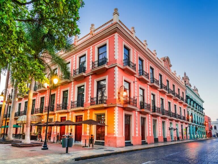 A colorful, historic building on a vibrant street corner with lush greenery and warm lighting; no visible persons or vehicles present.