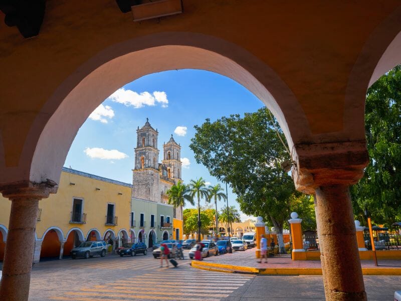 View of a church and park in Valladolid from under an archway.