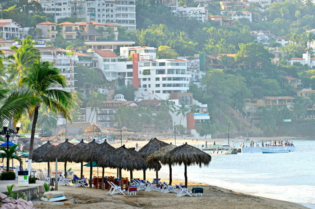 Huts near the beach surrounded by buildings.