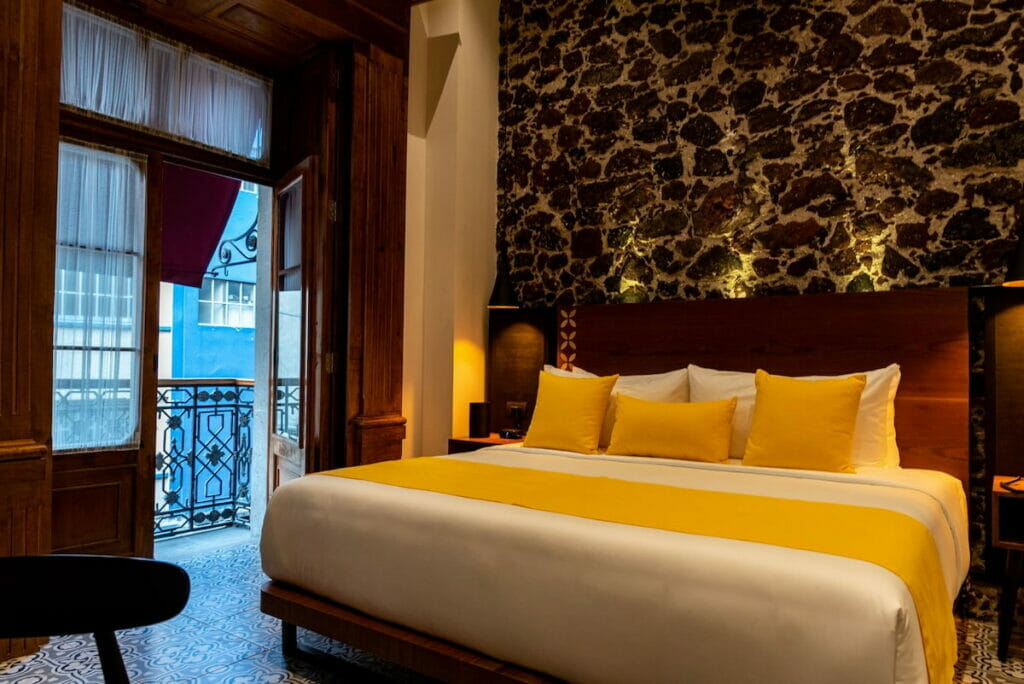 A hotel in Mexico City with a comfy bed with yellow sheets.
