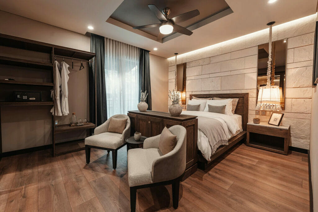 A Mexico City hotel with a spacious room with bed and a couple of accent chairs.