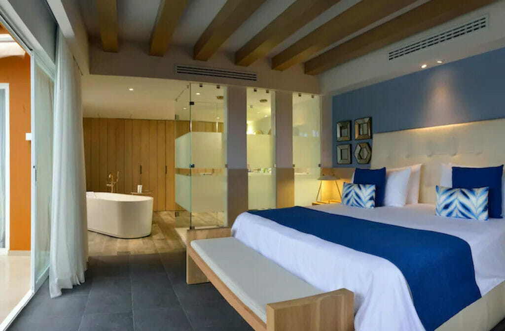 A hotel room in Catalonia in Punta Maroma with a cozy bed near the bathroom with a tub.