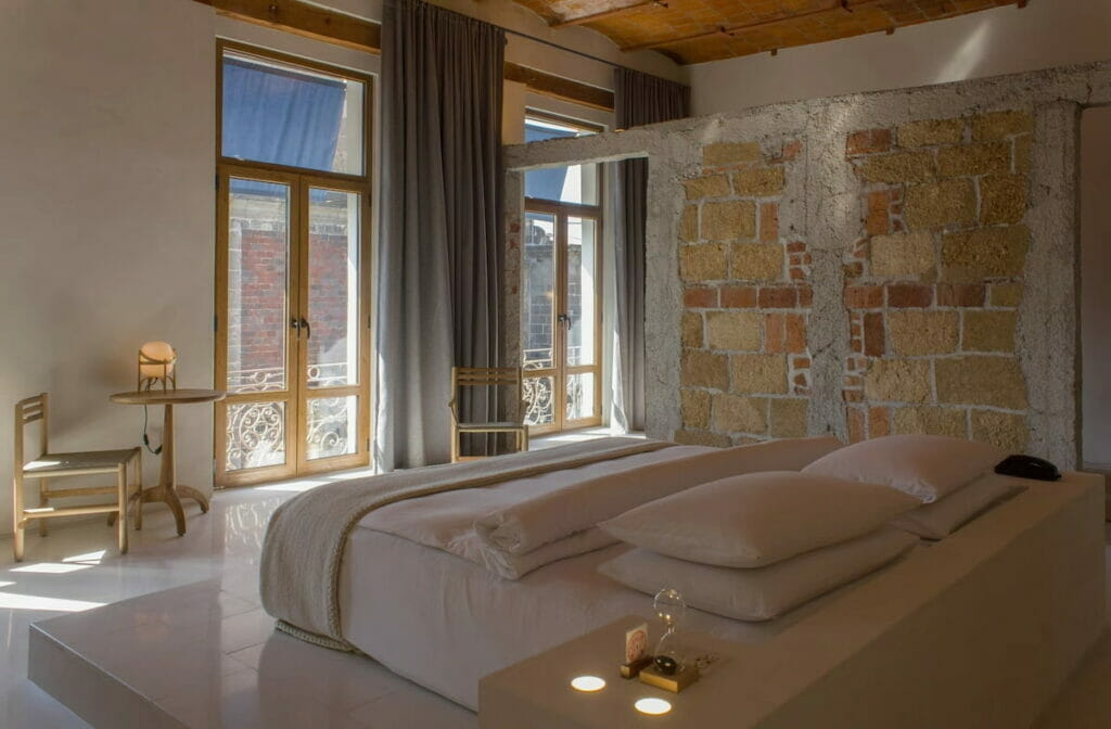 A cozy hotel in Mexico City with a bed and ceiling-to-floor windows.