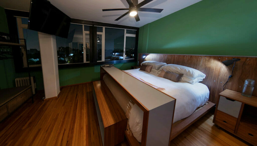 A green wall room with a bed and ceiling fan in Mexico City.