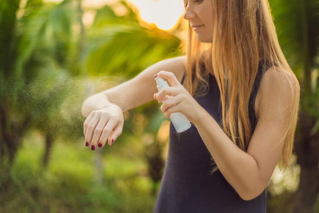 A woman using insect repellent on her arm.