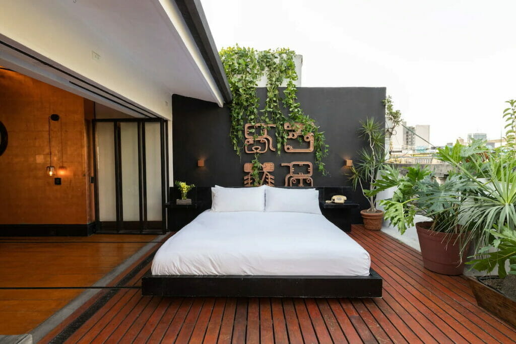 A bed placed on the balcony of a spacious room.