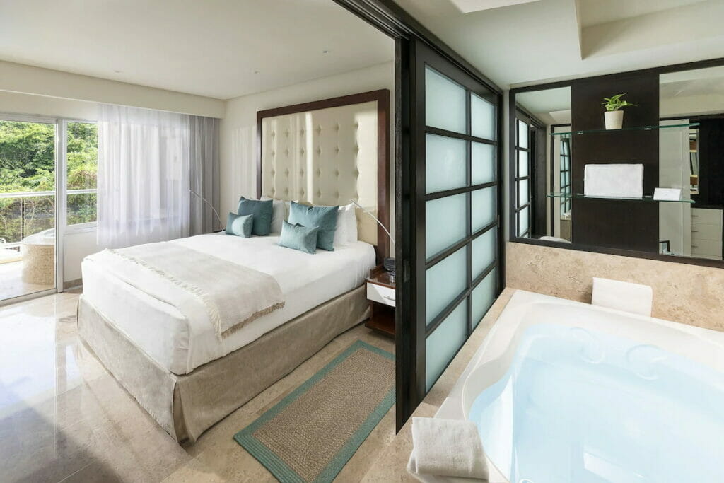 The Parasidus Playa del Carmen hotel with a cozy bed and a partition for the huge tub.