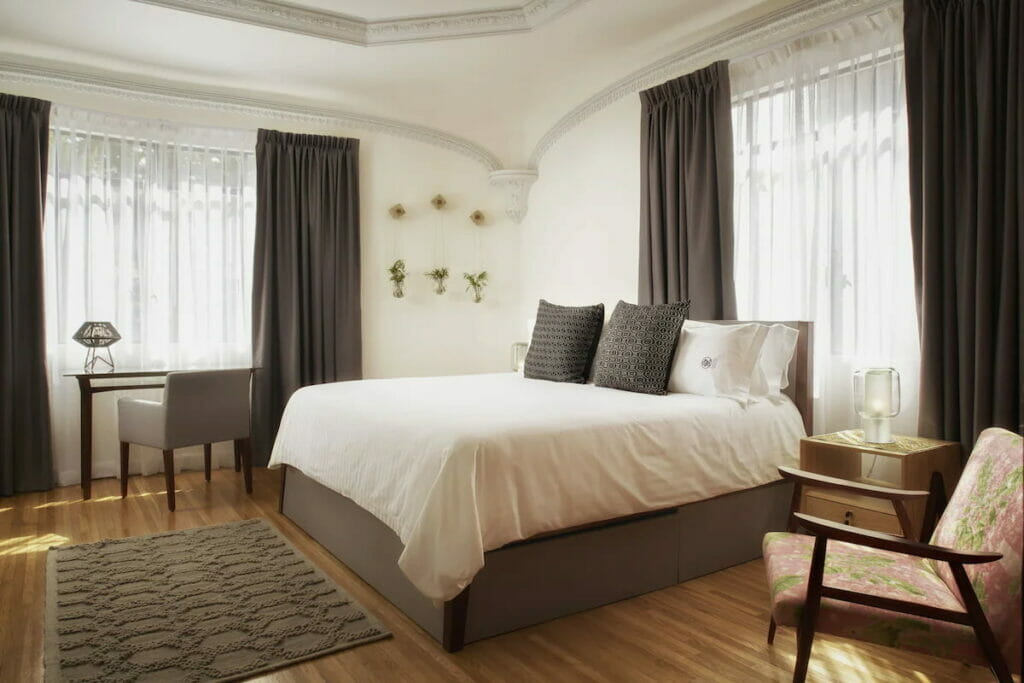 View of a bedroom near the small desk surrounded by windows.