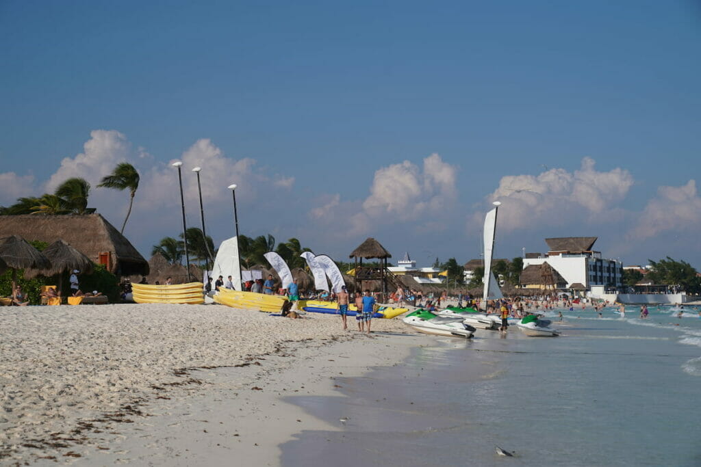Boats and people gather on the shore in Punta Maroma.