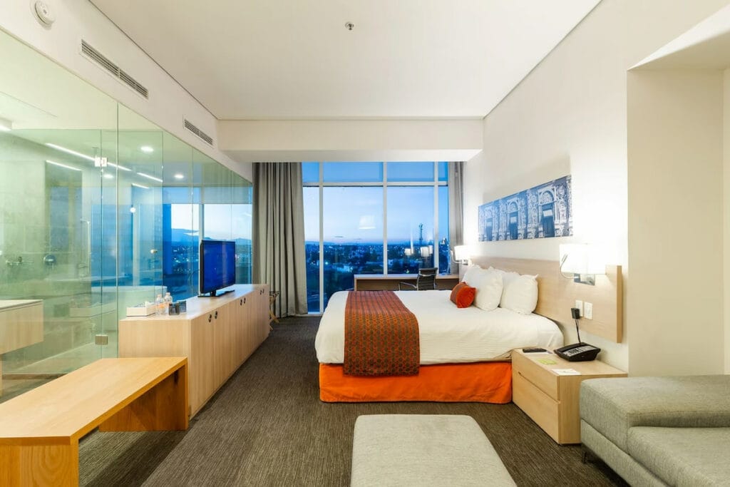 Hotel room with a beautiful view of the city from its windows at Camino Puebla.