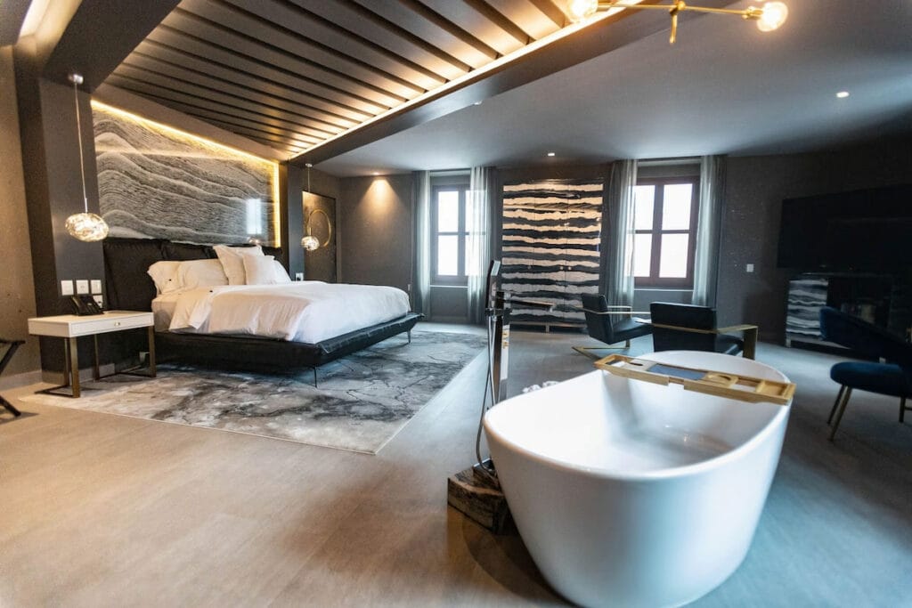 Spacious hotel room at Hotel Perla with a tub in the middle of the room.