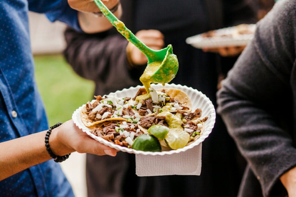 A man putting sauce on the Tacos al Pastor.