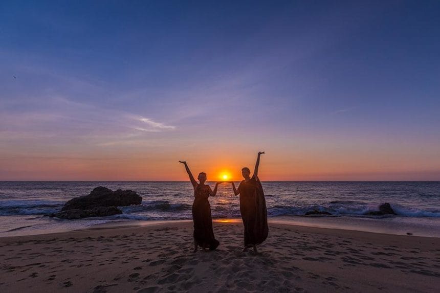 Two girls framing on the beach framing the sunset with their hands