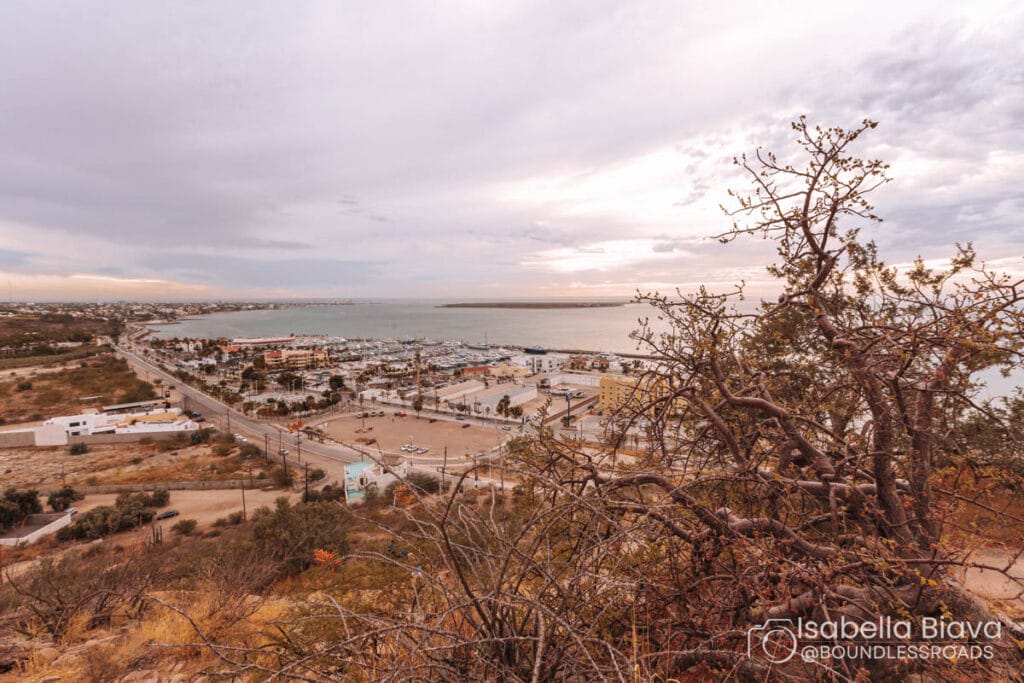 Overlooking La Paz, Baja California Sur, Mexico, the image captures a tranquil seascape, marina, and urban landscape under a cloudy sky.