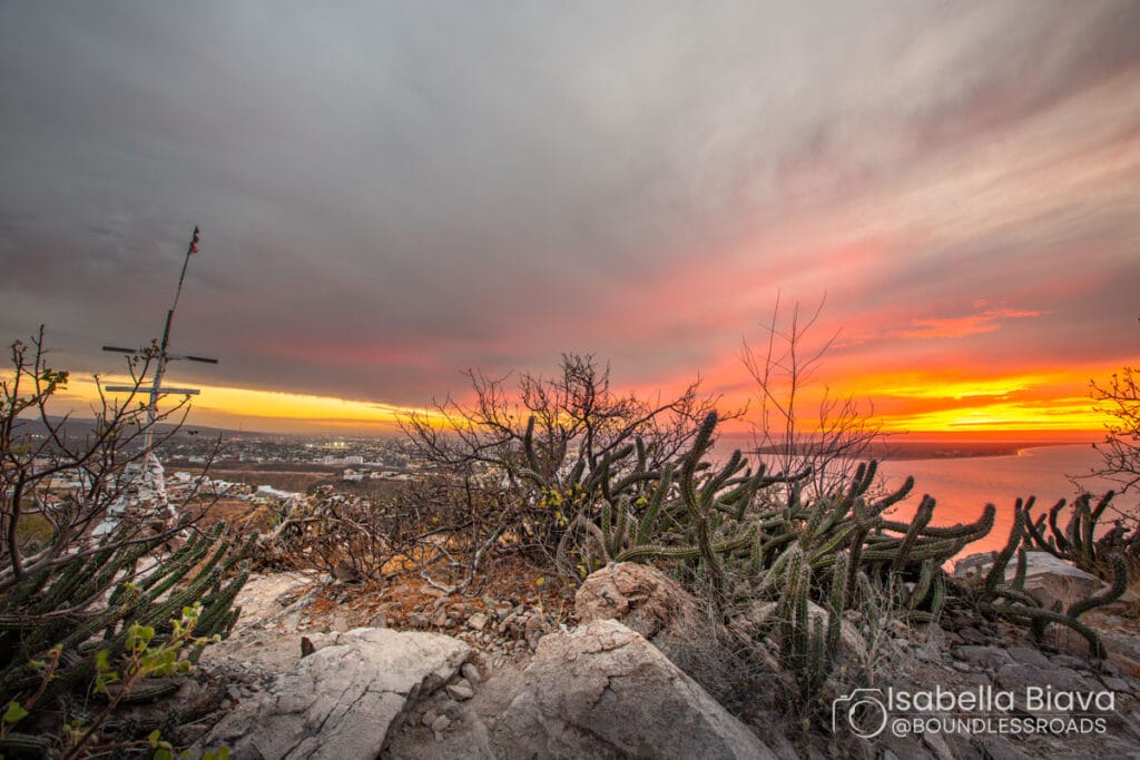 Sunset view from Cerro de la Calavera, rocky terrain with cacti and a scenic sky over La Paz, Baja California Sur coastline.