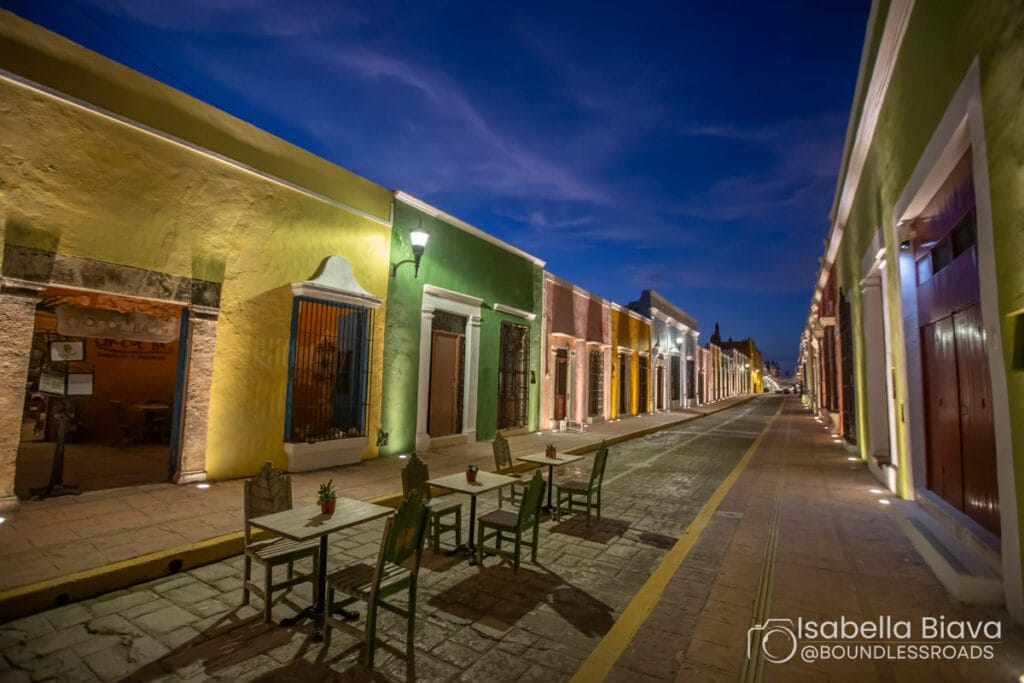 Colorful colonial street with outdoor cafe seating at night.