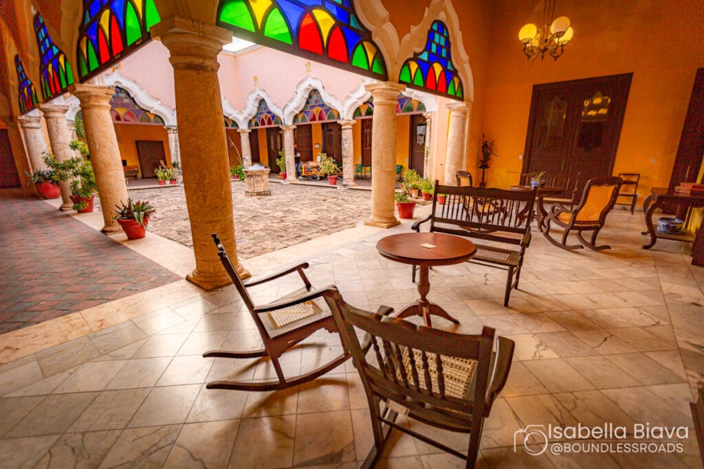 Colorful stained glass courtyard with wooden chairs.
