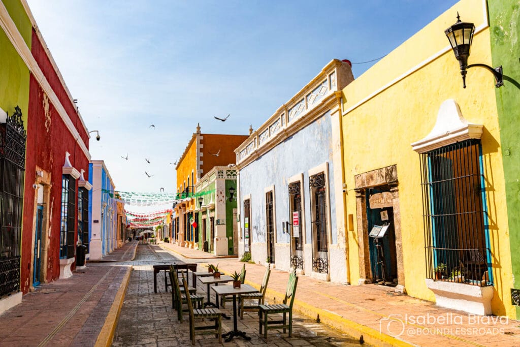 Colorful street in Campeche, Mexico with birds flying.