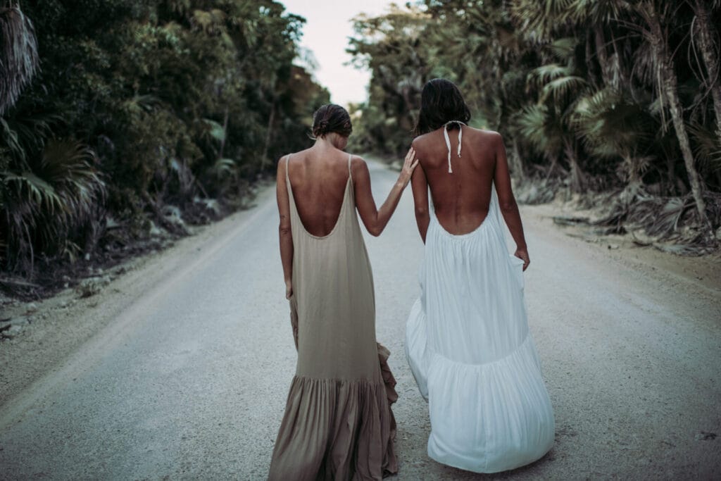 Two women walking in long dresses on road