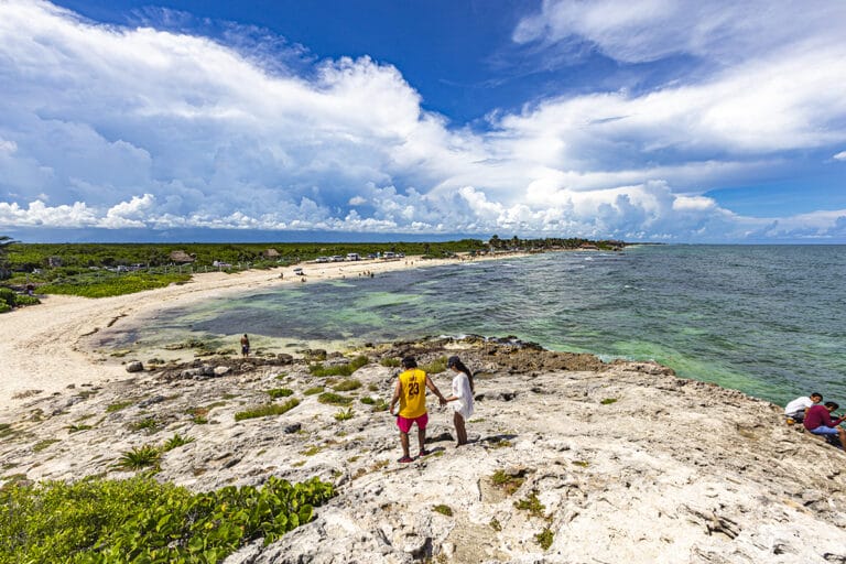 Couple walking along rocky Caribbean coastline.