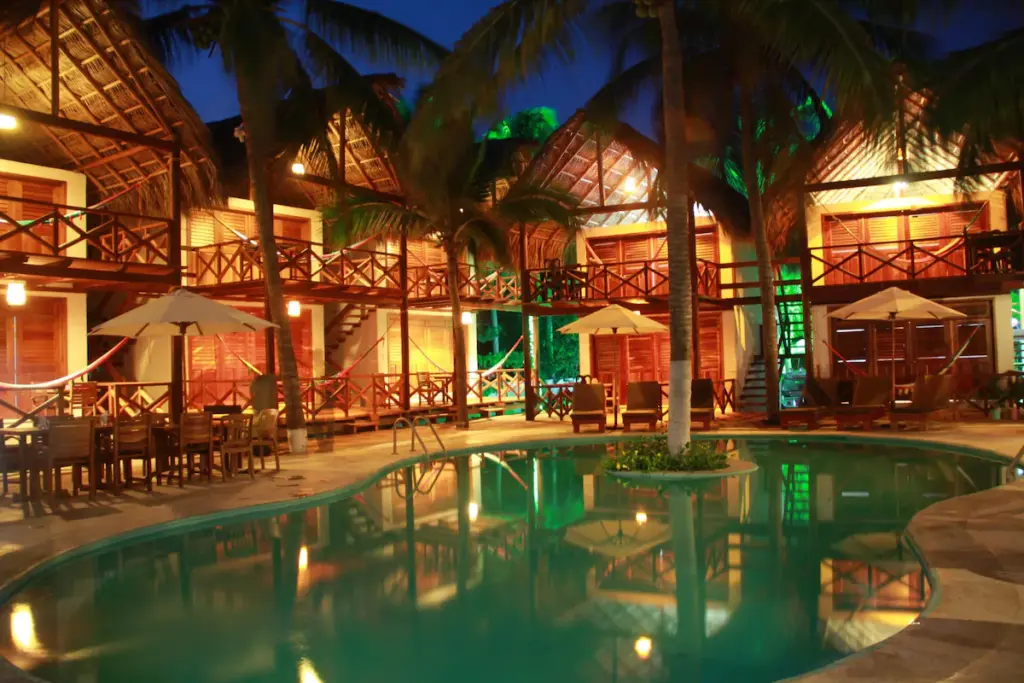 Luxurious tropical resort with illuminated pool at night.
