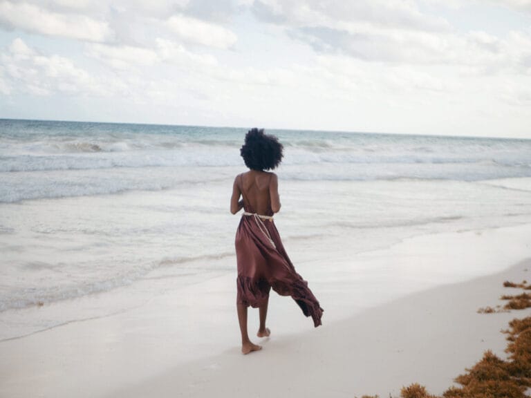 Woman walking on beach in flowing dress